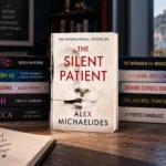 The Silent Patient displayed with similar psychological thrillers in a moody reading setup with coffee, notebook, books, and warm light
