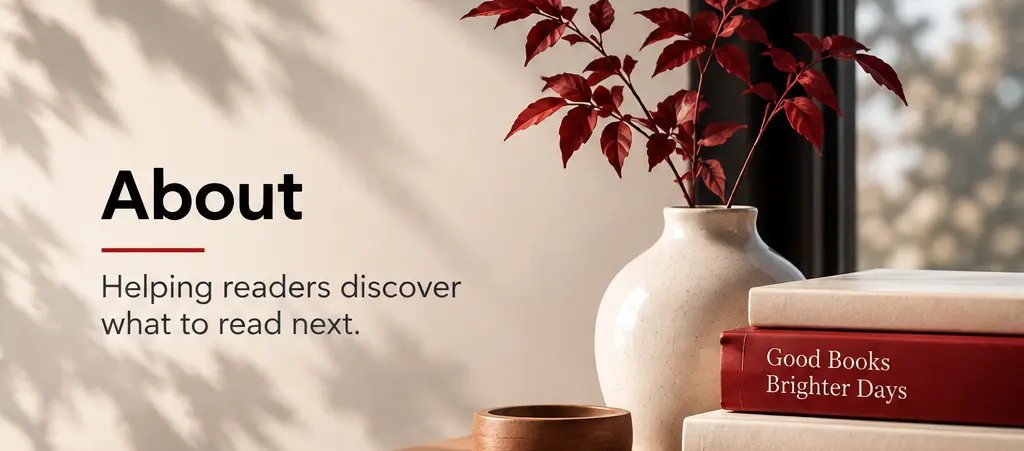 Warm editorial reading scene with stacked books, red branches, a ceramic vase, and soft natural light